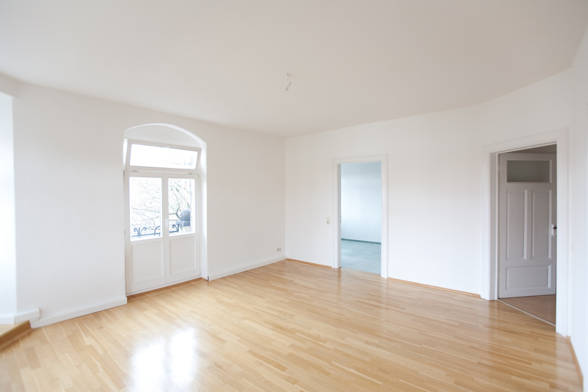 Empty all-white living room in a loft with tan wooden floors